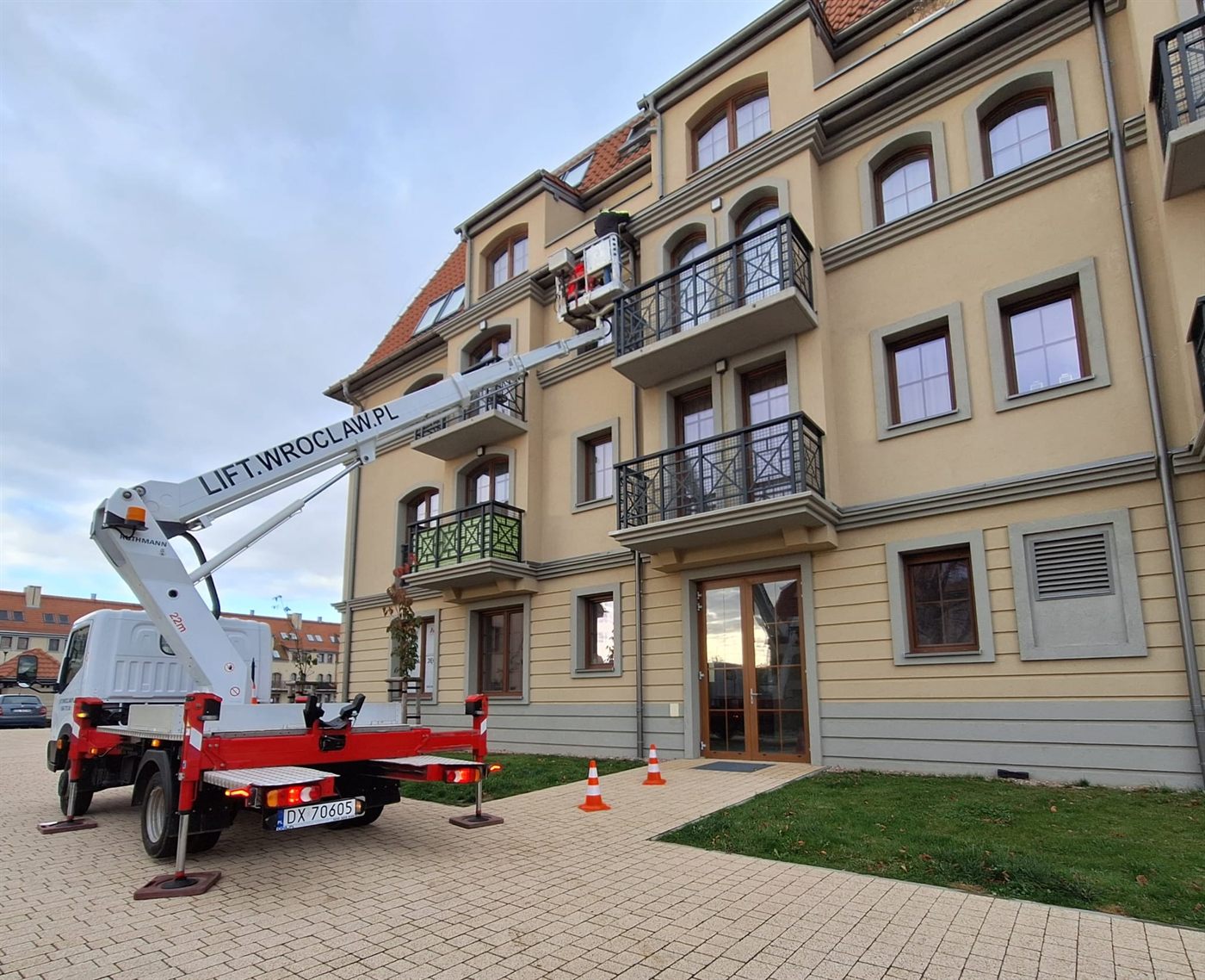 Podnośnik koszowy rozstawiony przy elewacji kamienicy