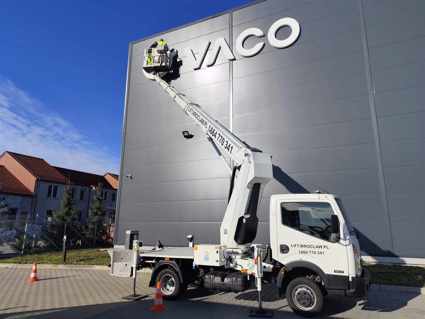 Mycie logotypu na elewacji budynku z kosza podnośnika